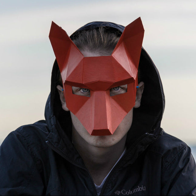 Person wearing a red Fox mask outdoors with a blurred background